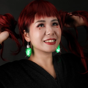 Close-up of a model wearing creative glowing green LED bulb earrings for Christmas parties