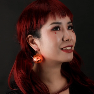 LED glowing orange pumpkin earrings for Halloween night club parties on a model