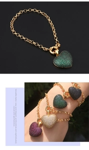 Detail eines Herzanhängers in Gold mit farbigem Zirkonia an einer groben Kette