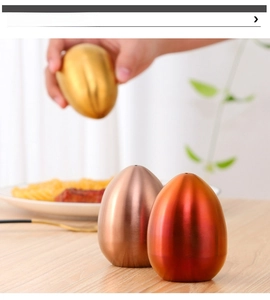 Macro view of egg-shaped stainless steel salt and pepper shakers in golden and rose gold