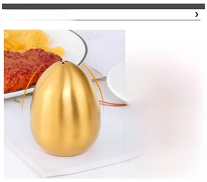 Close-up of egg-shaped gold stainless steel spice shaker with top holes and brushed texture