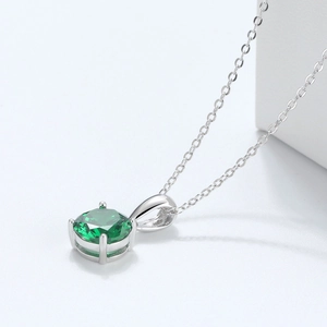 Close-up of S925 silver pendant necklace with four-prong set round green gemstone