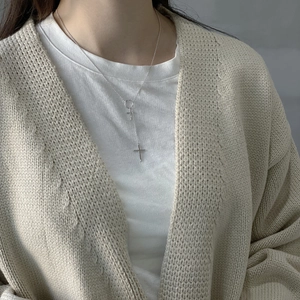 Detailed view of silver Y-shaped cross necklace with dual pendants on model
