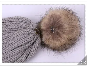 Détail d'un bonnet en tricot gris avec pompon amovible en fausse fourrure et bouton