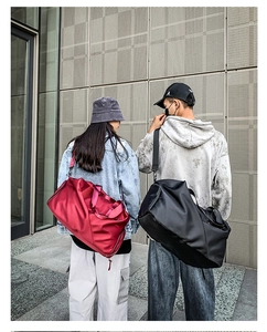 Outdoor view of travel bags in red and black colors carried by models on modern street