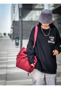 Red nylon travel duffel bag with large capacity worn over the shoulder by a model outdoors