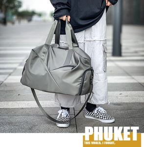 Close-up of gray nylon duffel bag with handles and adjustable strap on a city street