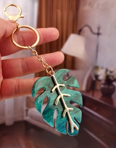 Detail of handcrafted emerald monstera leaf keychain with golden veins and sequins