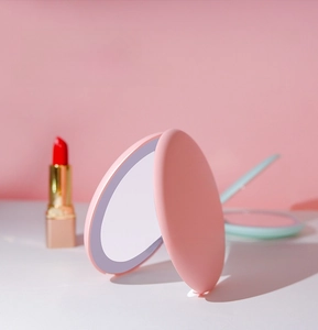 Pink foldable LED makeup mirror with soft lighting and 2X magnification feature