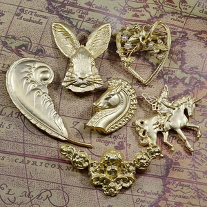 Detailed close-up of six vintage matte gold brooches featuring unicorn and angel designs