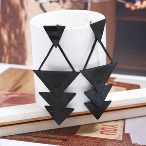 Détail de boucles d'oreilles pendantes géométriques noires sur une tasse blanche
