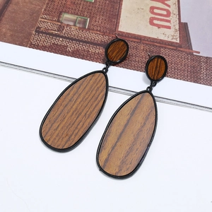 Détail de boucles d'oreilles en bois en forme de goutte dans un cadre en métal noir