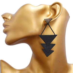 Détail de boucles d'oreilles triangles noirs en bois sur une tête de mannequin dorée