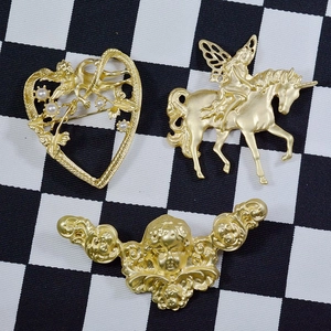 Retro matte gold unicorn fairy and heart angel brooches on a checkered background