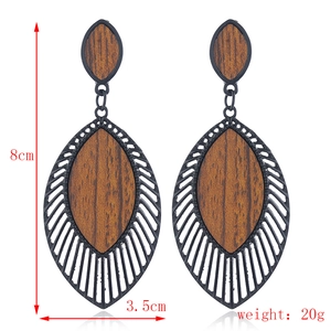 Détail de boucles d'oreilles feuilles en bois et métal avec dimensions de 8cm et 3.5cm