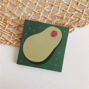 Nahaufnahme von quadratischen Haftnotizen mit lächelnder Avocado auf dunkelgrünem Grund