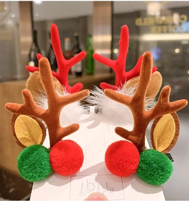 Close-up of Christmas reindeer antler hair clips with red and green plush pom-poms