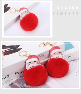 Close-up of fluffy red pom-pom keychain with Santa Claus leather patch and gold metal ring