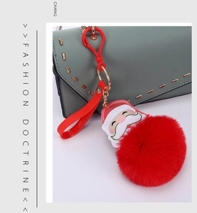 Close-up of Santa Claus plush ball keychain with golden metal clasp on a handbag