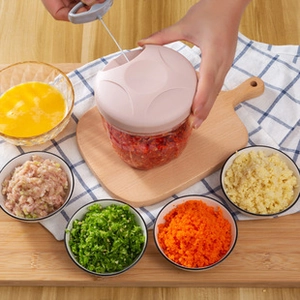Close-up of a pink manual food chopper on a wooden board with minced ingredients