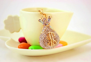 Macro shot of gold money bag keychain with crystal rhinestones and dollar symbol
