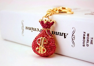 Detailed macro of a gold money bag keychain with sparkling pink crystals and $ sign