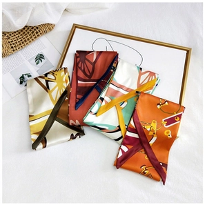 Detailed flat lay of long silk scarves in four patterns with artistic props on white background