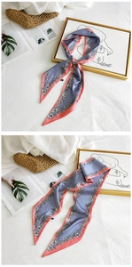 Close-up of gray-blue floral silk scarf styled on a woven bag and magazine