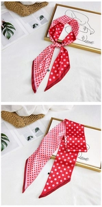 Detailed view of red and pink polka dot silk scarf tied on a stylish white background