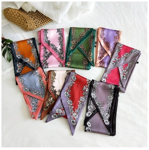 Flat lay of colorful floral silk scarves and hair ribbons on a white textured background