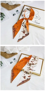 Detail of orange and beige silk scarf with floral patterns on minimalist white background
