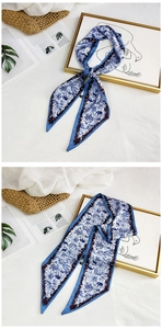 Detail view of blue silk scarf featuring artistic elephant and giraffe animal patterns