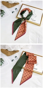 Detail of a long silk scarf with horse patterns used as an accessory for a straw bag