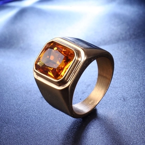 Détail macro d'une bague dorée pour homme avec pierre orange carrée et fini brossé