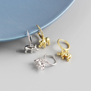 Detail view of silver and gold rhino hoop earrings displayed on a minimalist blue plate