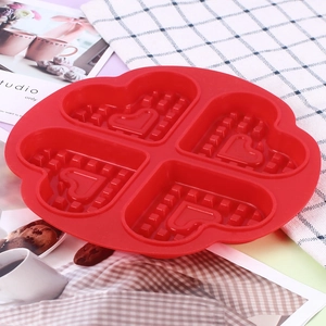 Close-up of red heart-shaped silicone waffle mold with four cavities in a baking scene