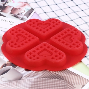 Detail view of heart-shaped four-cavity red silicone waffle mold on decorative surface