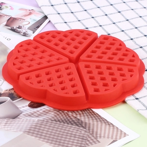 Top view of a bright red heart-shaped silicone waffle mold on a grid tablecloth background