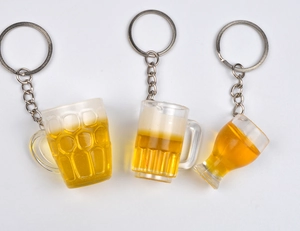 Dettaglio di mini portachiavi a boccale di birra in resina dorata con schiuma realistica
