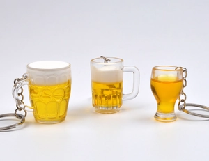 Dettaglio di tre portachiavi mini boccale di birra con schiuma e liquido giallo realistico