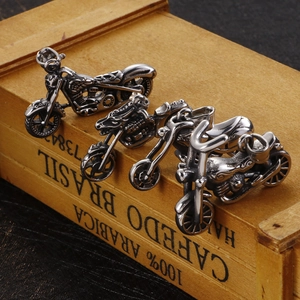 Three punk style stainless steel motorcycle skull pendants on a vintage wooden background