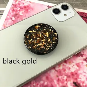 Detail of round black and gold foil phone socket stand on white smartphone surface