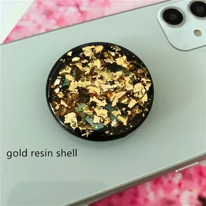 Macro shot of circular resin phone grip with luxury gold foil and blue shell inlay