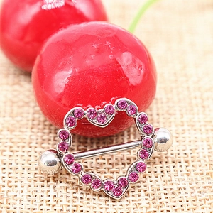 Macro shot of silver heart nipple shield with pink rhinestones on a rustic burlap background