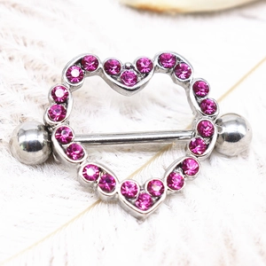 Detailed close-up of heart-shaped nipple ring with pink crystals on white feather background