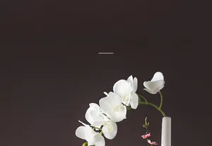Detail einer weißen Keramikvase mit horizontaler Textur und Orchideenblüten-Arrangement