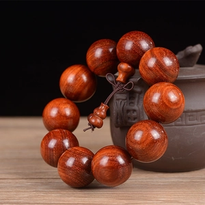 Macro detail of 25mm sandalwood prayer beads with natural grain and golden flecks