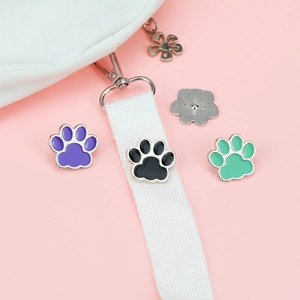 Detail of colorful paw print enamel pins with smooth finish on pink background