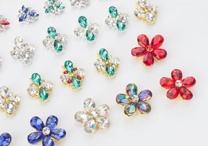 Detailed view of 3D metal five-petal flower nail art charms in colorful rhinestone finishes