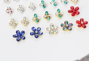 Macro shot of 3D metal flower nail charms with colorful crystals and gold metal bases